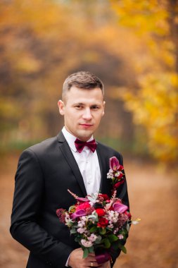 Baharın bahçesindeki ağaçların arasında duran mutlu nişanlı..