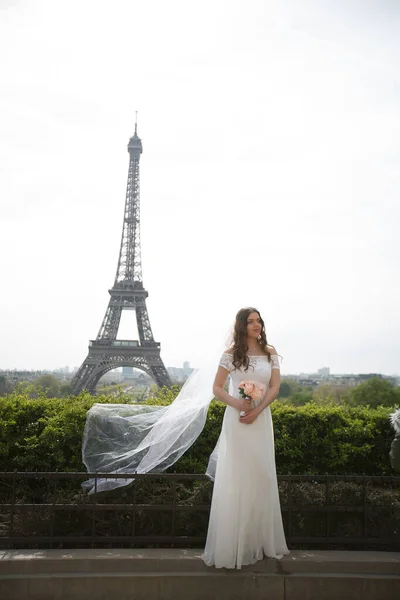 Beautiful bride in rich wedding dress whirls on the square before the Eiffel Tower — Stock Photo, Image
