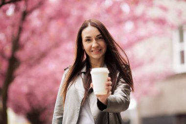 Kız ve Sakura. Güzel genç bir kadın güzel bir bahar gününde kiraz çiçeği mevsiminde parkta güneşli bir günün tadını çıkarıyor.