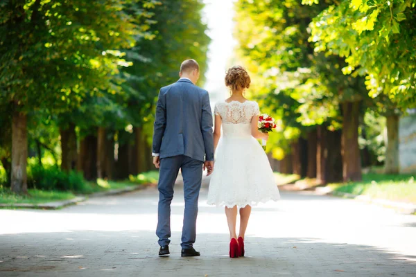 結婚式の日に花嫁と新郎は、自然の中で屋外を歩く. — ストック写真