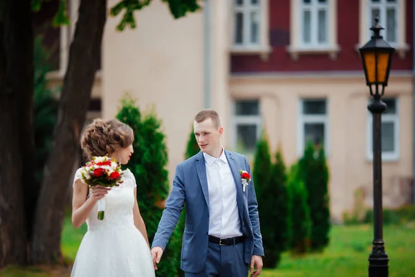 Bride and groom on their wedding day, walking outdoors in nature. — Stock Photo, Image