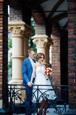 Şık gelin ve damat düğün günü dışarıda birlikte poz veriyorlar.