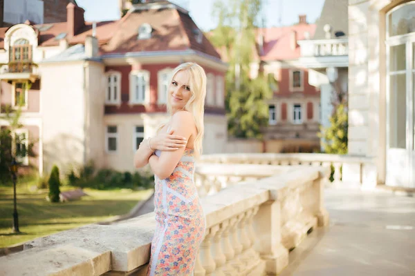 Preciosa joven modelo mujer con perfecto pelo rubio mirando a la cámara posando en la ciudad en vestido . — Foto de Stock