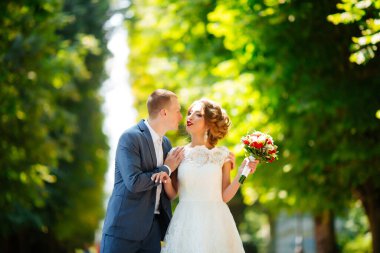 Şık gelin ve damat düğün günü dışarıda birlikte poz veriyorlar.