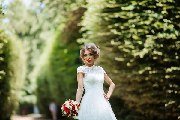 Beautiful bride with a wedding bouquet in her hands outdoors in the park. — Stock Photo, Image