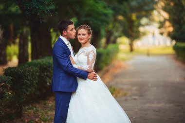 Düğün çifti, beyaz gelinlik içinde gelin ve damat ormanda yürüyor, dans ediyor ve gülümsüyor.