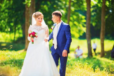 Şık gelin ve damat düğün günü dışarıda birlikte poz veriyorlar.