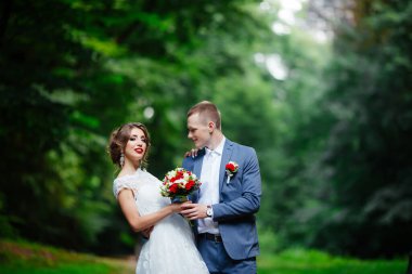 Şık gelin ve damat düğün günü dışarıda birlikte poz veriyorlar.