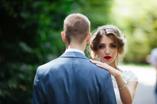 結婚式のカップル幸せな新婚夫婦と夫は緑の公園で抱き合って. — ストック写真