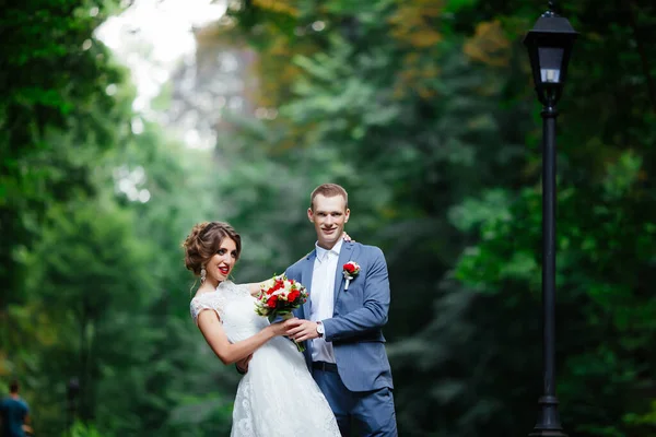 Bride and groom on their wedding day, walking outdoors in nature. — Stock Photo, Image