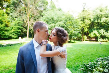 Şık gelin ve damat düğün günü dışarıda birlikte poz veriyorlar.