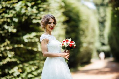 Şık gelin ve damat düğün günü dışarıda birlikte poz veriyorlar.