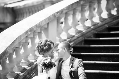 Şık gelin ve damat düğün günü dışarıda birlikte poz veriyorlar.