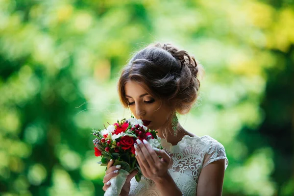 Брюнетка наречена в весільній сукні і букет на заході сонця в парку — стокове фото