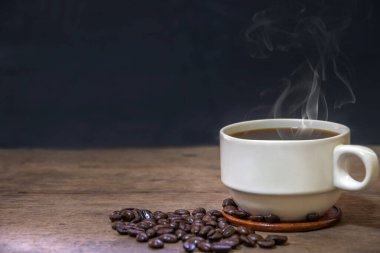 Bir fincan sıcak espresso kahve fincanı ve kavrulmuş kahve çekirdekleri ahşap zemin zeminine, kahve sabahı, seçici odak noktası.