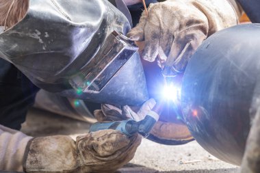 İnşaat işçisi ağır bir şantiyedeki boruları kaynak yapıyor..