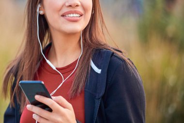 Modern young woman with cellphone making pause during jogging / 