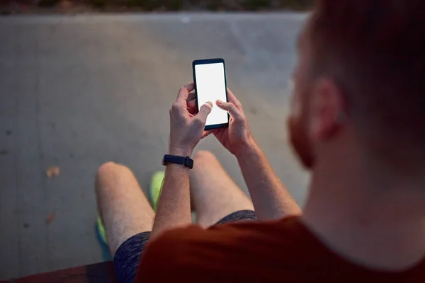 Muž používající mobil v městském parku v noci. — Stock fotografie