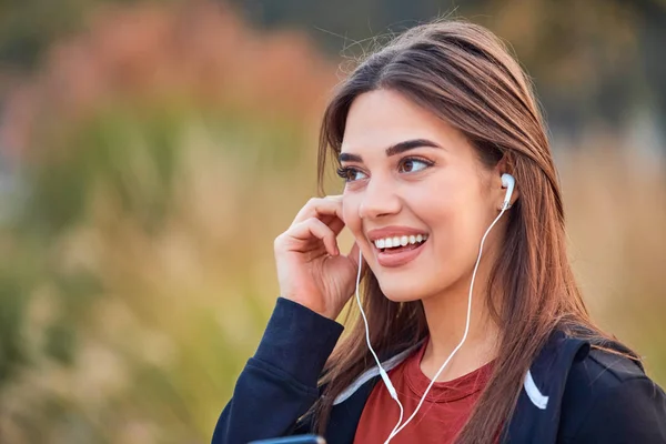 Modern young woman with cellphone making pause during jogging / — Stockfoto