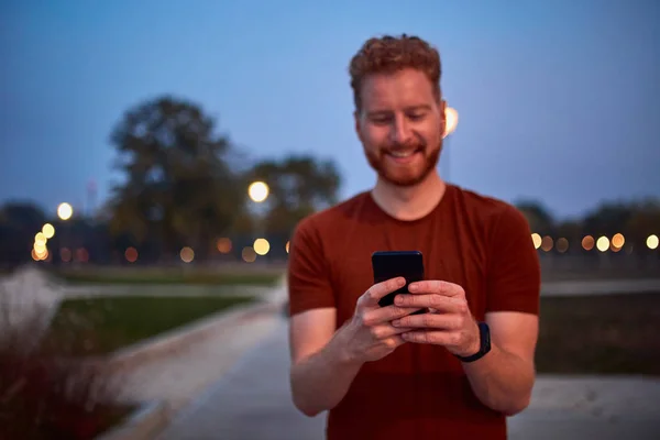 Homem usando celular no parque urbano à noite . — Fotografia de Stock