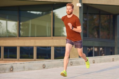 Şehir parkında spor yapan / koşan genç adam.
