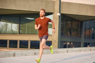 Şehir parkında spor yapan / koşan genç adam.