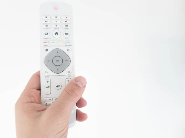 Hand holding TV remote controller on a white background.