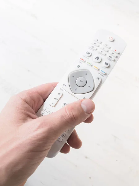 Hand holding TV remote controller on a white background.