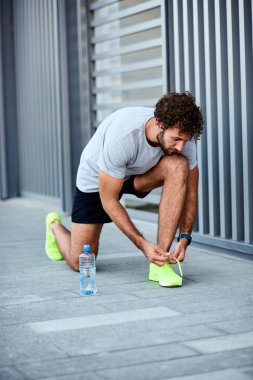 Sokakta koşu ayakkabısı bağlayan adam..