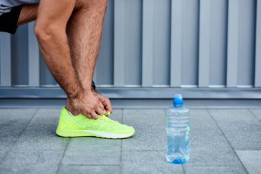 Sokakta koşu ayakkabısı bağlayan adam..