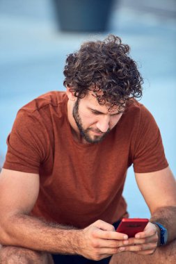 Parkta modern cep telefonu kullanan genç bir adam..