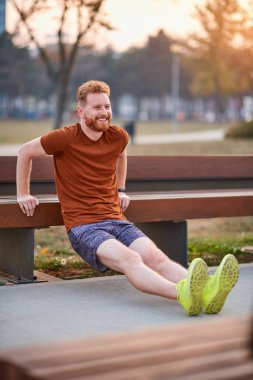 Genç adam şehir parkında egzersiz yapıyor / esniyor.