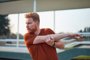 Genç adam şehir parkında egzersiz yapıyor / esniyor.