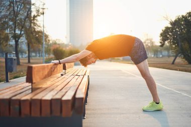 Genç adam şehir parkında egzersiz yapıyor / esniyor.