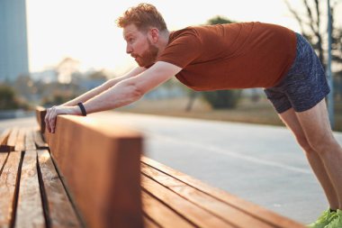 Genç adam şehir parkında egzersiz yapıyor / esniyor.