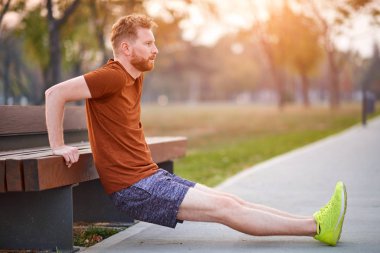 Genç adam şehir parkında egzersiz yapıyor / esniyor.