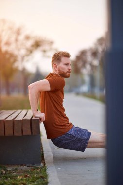 Genç adam şehir parkında egzersiz yapıyor / esniyor.