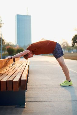 Genç adam şehir parkında egzersiz yapıyor / esniyor.