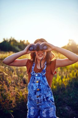 Doğada dürbün kullanan küçük kız..