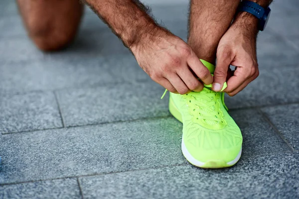 Hombre atando zapatillas en la calle . — Foto de Stock