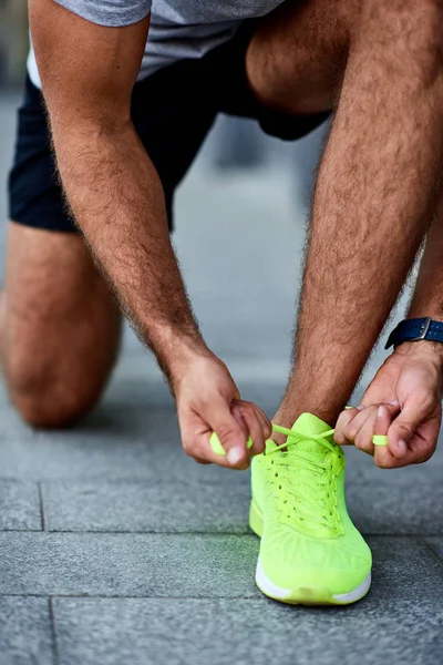 Man tying running shoes on the street.