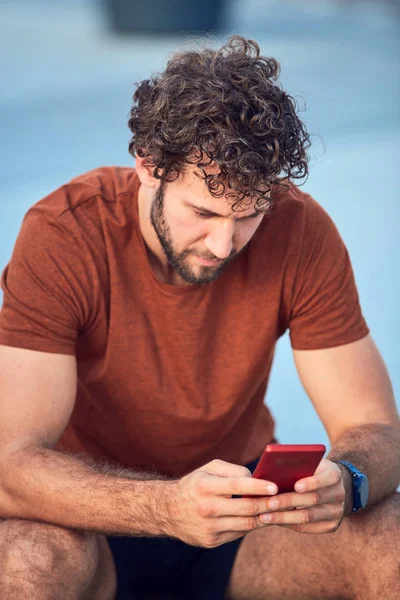 Homem adulto jovem usando celular moderno no parque . — Fotografia de Stock