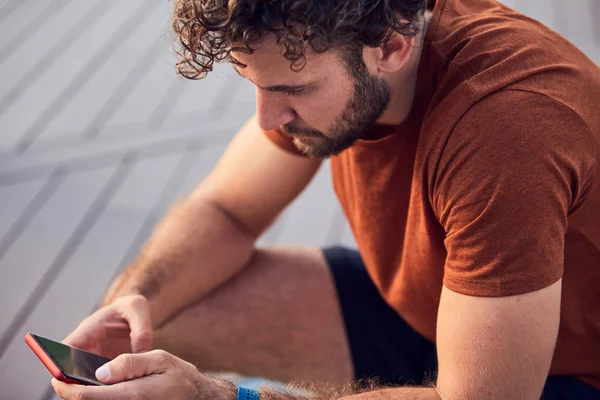 Homem adulto jovem usando celular moderno no parque . — Fotografia de Stock