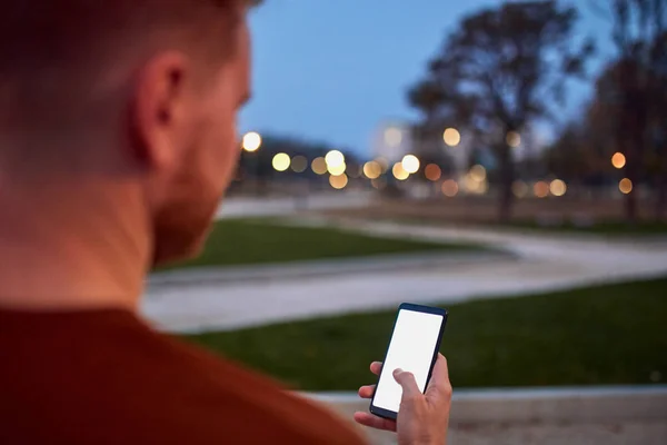 Homem usando celular no parque urbano à noite . — Fotografia de Stock