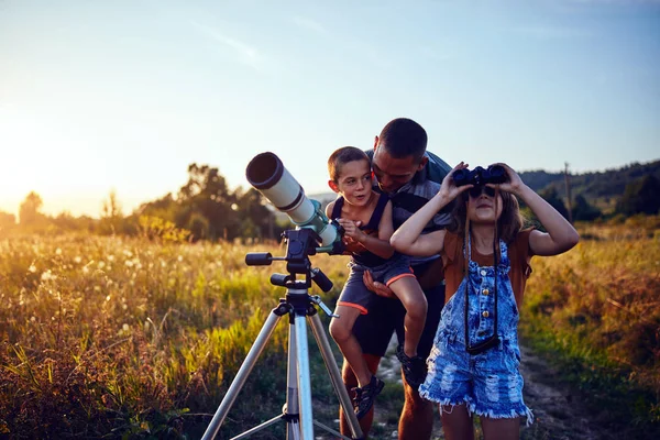 Vader, dochter en zoon observeren de lucht met een telescoop. — Stockfoto