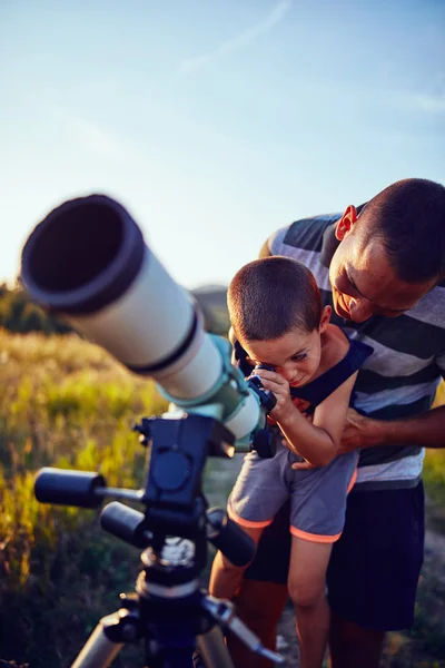 Vater und Sohn beobachten den Himmel mit dem Teleskop. — Stockfoto