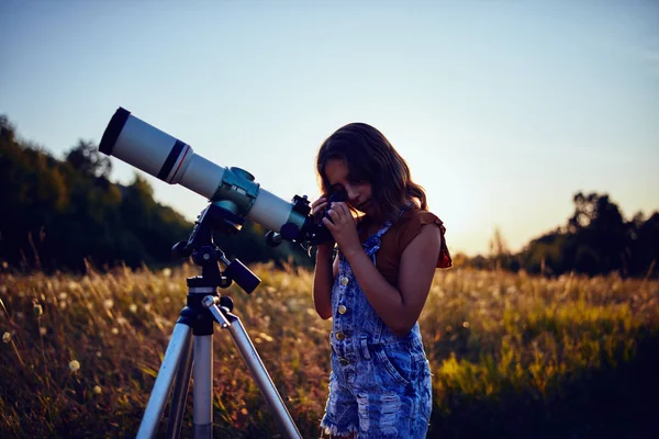 Küçük kız evreni keşfetmek için doğada teleskop kullanıyor.. — Stok fotoğraf