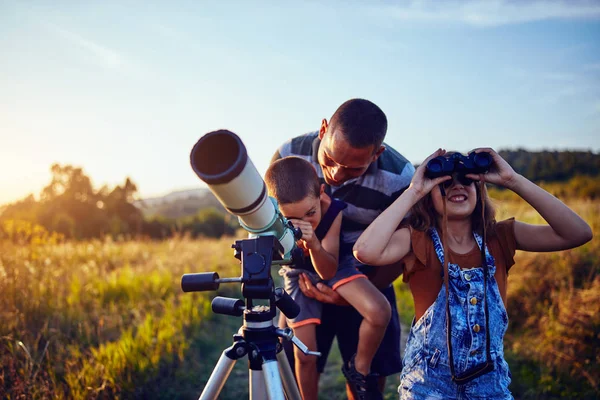 Vater, Tochter und Sohn beobachten den Himmel mit dem Teleskop. — Stockfoto