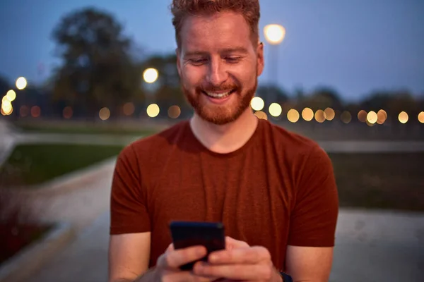 Homem usando celular no parque urbano à noite . — Fotografia de Stock