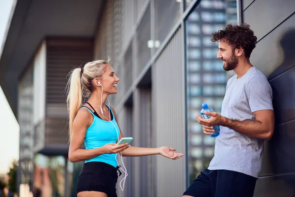 Hombre y mujer jóvenes modernos haciendo una pausa después de trotar / hacer ejercicio — Foto de Stock